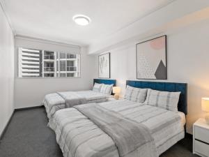 two beds in a bedroom with white walls at City Centre Apartment New Furnitures in Brisbane