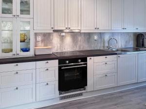 eine Küche mit weißen Schränken und einem schwarzen Backofen in der Unterkunft 4 person holiday home in Stonglandseidet-By Traum in Stonglandseidet