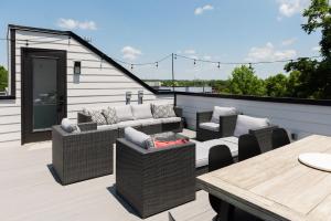 a patio with wicker furniture and a wooden table at The Adelaide - Downtown Luxury & Charming Rooftop in Nashville