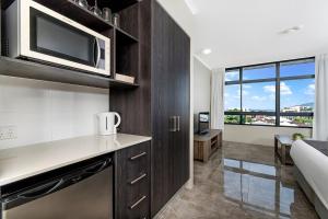 a kitchen with a microwave and a living room at Sunshine Tower Hotel in Cairns