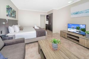 ケアンズにあるサンシャイン タワー ホテルのベッドとテレビがあるホテルの部屋