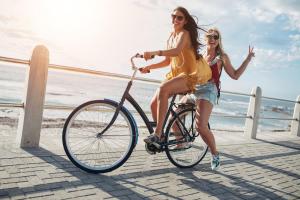 two young women riding a bike on a boardwalk at Haus Miramar 09 in Ahlbeck