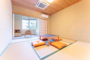 Cette chambre comprend une table et deux oreillers orange. dans l'établissement Noёl HAKONE GENSEN, à Hakone