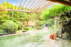 a swimming pool with a waterfall in a backyard at Ooedo Onsen Monogatari Shinshu Kakeyu in Ueda