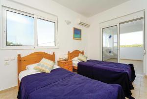 a bedroom with two beds with purple sheets and windows at Royal St.Georges in Fánai