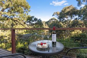 a table with a bottle of wine and a bowl of fruit at Otway Rest in Lorne