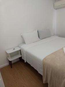 two beds in a small room with a night stand at Sonho 2 Guest House in Búzios