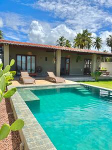a villa with a swimming pool in front of a house at Casa Palma in São Miguel do Gostoso