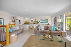 a living room with two couches and a kitchen at Allure By The Sea in Bonny Hills