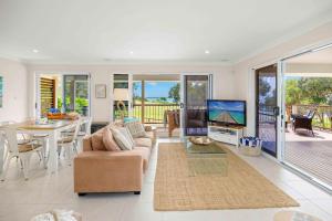 a living room with a couch and a tv and a table at Allure By The Sea in Bonny Hills