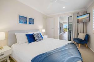 a bedroom with a large bed with blue pillows at Allure By The Sea in Bonny Hills