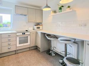uma cozinha com armários brancos e um balcão em The Hollies em Weston-super-Mare
