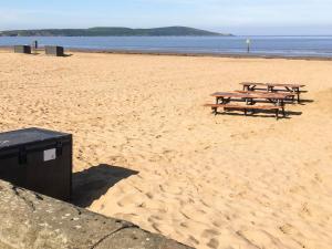 three picnic tables on a beach near the water at The Hollies in Weston-super-Mare