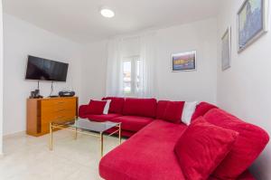 a living room with a red couch and a tv at Apartment Oblutak in Brodarica