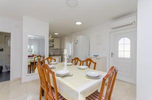 a white dining room with a white table and chairs at Apartment Oblutak in Brodarica +16 photos