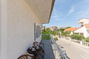 a balcony with a table and chairs and a street at Apartment Oblutak in Brodarica