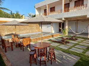 a patio with a table and chairs and an umbrella at Recanto pais e filho in Monte das Gameleiras