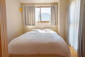 DC桜の苑401洋式双人床 في أوساكا: سرير أبيض في غرفة نوم مع نافذة