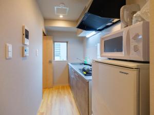 uma pequena cozinha com frigorífico e micro-ondas em DC桜の苑401洋式双人床 em Osaka