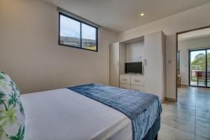 a bedroom with a bed and a flat screen tv at Muna Tamarindo in Tamarindo