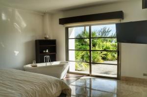 a bedroom with a bed and a tub and a window at Departamento de lujo con playa y marina en Cancun-La Amada in Cancún