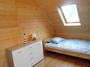 1 dormitorio en una cabaña de madera con cama y ventana en Comfortable holiday homes for 7 people, Niechorze, en Niechorze