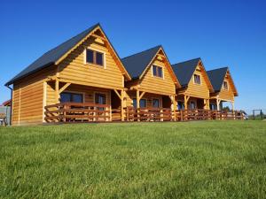 a row of log homes on a grass field at Comfortable holiday homes for 7 people, Niechorze in Niechorze