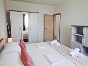 ein Schlafzimmer mit einem großen weißen Bett mit roten Kissen in der Unterkunft Apartment in Sveta Marija Magdalena, by the sea with sea view in Barić Draga