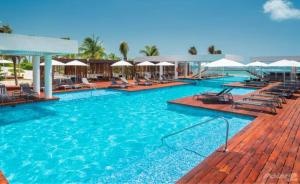 a large swimming pool with chairs and umbrellas at Departamento de lujo con playa y marina en Cancun-La Amada in Cancún