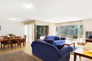a living room with a blue couch and a table at Kamillaroi Walk to restaurants cafes and beach in Nelson Bay