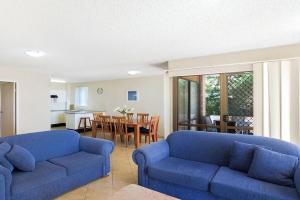 a living room with two blue couches and a kitchen at Kamillaroi Walk to restaurants cafes and beach in Nelson Bay