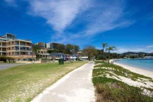 a walkway next to a beach with a building at Kamillaroi Walk to restaurants cafes and beach in Nelson Bay