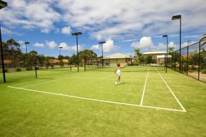 a young girl playing tennis on a tennis court at Oaks Pacific Blue Pool spa more in complex in Salamander Bay