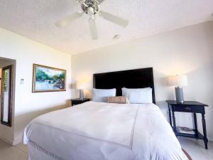 a bedroom with a large white bed with a ceiling fan at Oceanside Villa @ Ocho Rios, Jamaica Getaway in Boscobel