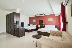 a hotel room with two beds and a couch at La Bonita Hotel and Apartments in Ho Chi Minh City