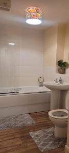 a bathroom with a tub and a toilet and a sink at Cozy Comforts 2 bed apartment Central Warrington in Warrington