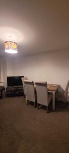 ein Esszimmer mit einem Tisch, Stühlen und einem TV in der Unterkunft Cozy Comforts 2 bed apartment Central Warrington in Warrington