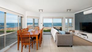 ein Wohnzimmer mit einem Tisch, einem Sofa und einem TV in der Unterkunft Hear the waves watch the whales Anna Bay in Anna Bay
