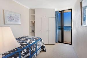 a bedroom with a bed and a view of the ocean at Gorgeous Harbourside with Stunning views in Soldiers Point