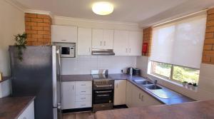 a kitchen with white cabinets and a stainless steel refrigerator at Seaspray Walk to the beach in Nelson Bay