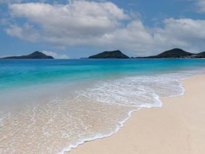 a sandy beach with two islands in the ocean at Seaspray Walk to the beach in Nelson Bay