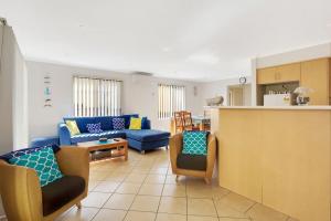 a living room with a blue couch and a kitchen at Townhouse in the heart of Port Stephens in Salamander Bay
