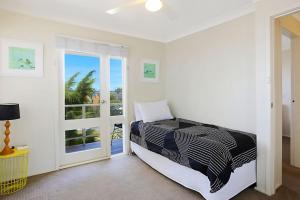a bedroom with a bed and a glass door at Views of Wanda Beach in Salamander Bay