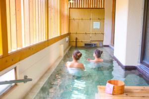 zwei Frauen im Wasser in einem Schwimmbad in der Unterkunft Ooedo Onsen Monogatari Hotel Shinko in Fuefuki