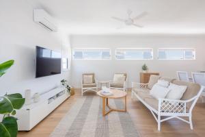 a living room with a couch and a tv at Biirinba Top Floor - oceanstays in Yamba