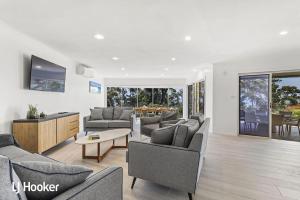 uma sala de estar com sofás e cadeiras e uma mesa em Osprey Waterfront Reserve Nelson Bay em Nelson Bay