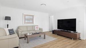 a living room with a couch and a flat screen tv at Absolute Waterfront Anna Bay in Anna Bay