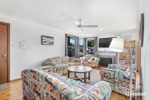 a living room with two couches and a table at Cromarty Beach Cottage in the Heart of Anna Bay in Anna Bay