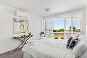 a white bedroom with a large bed and a window at Birubi Beach Waterfront in Anna Bay