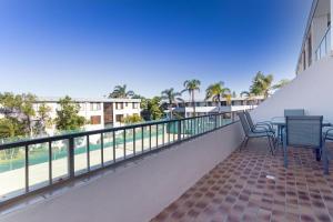 a balcony with a table and chairs and a view of the water at The Dunes Two bedroom apartment overlooking pool in Fingal Bay